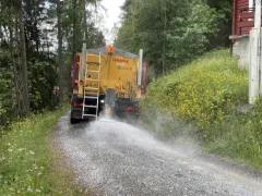 Falköping tallerkenspreder sprer støvdemping på grusvei om sommeren