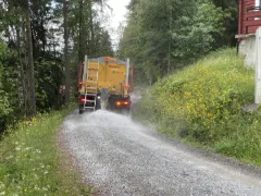 Støvdemping av grusvei med tallerkenspreder, sett bakfra